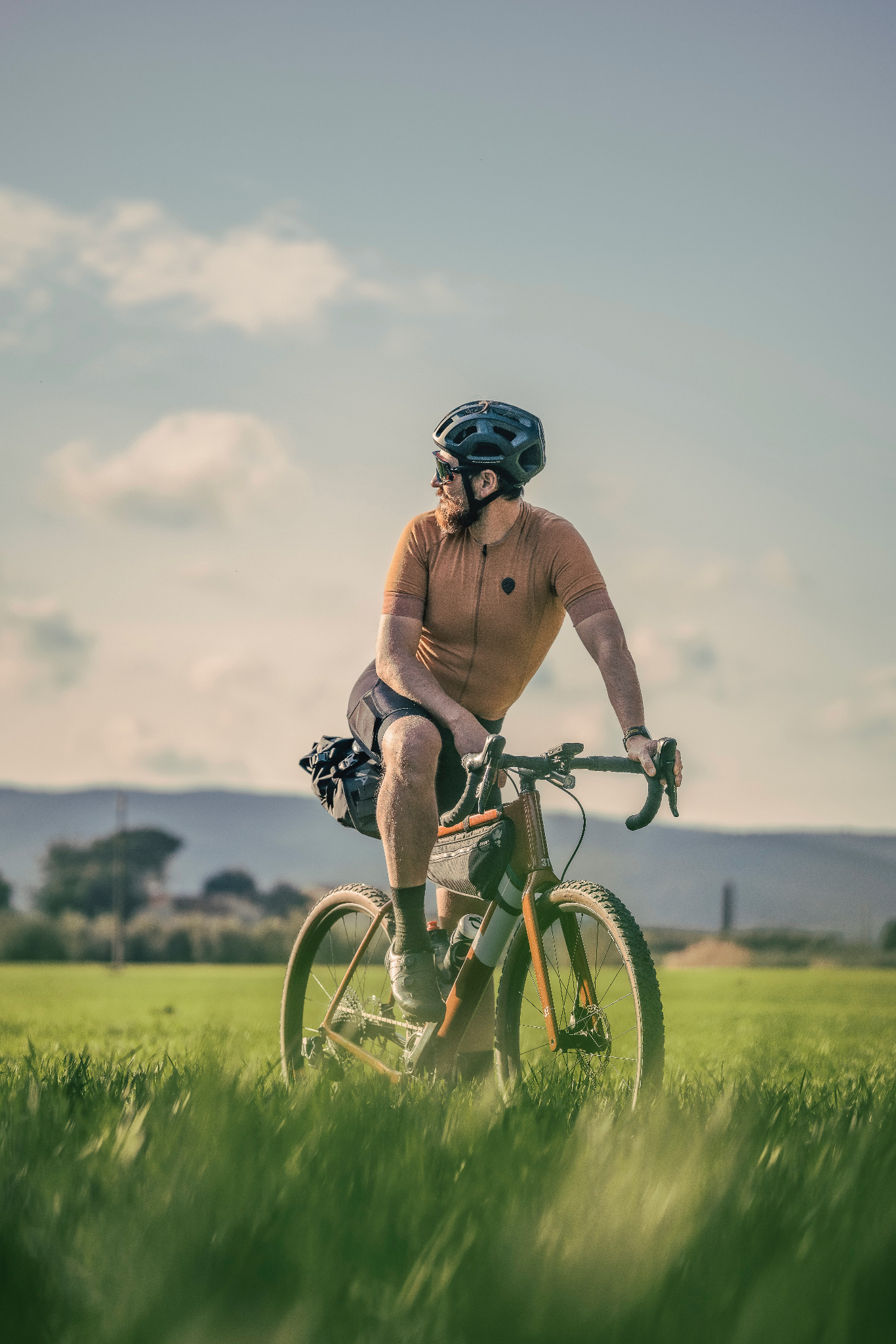 Ciclista su una bici gravel tra prati e colline